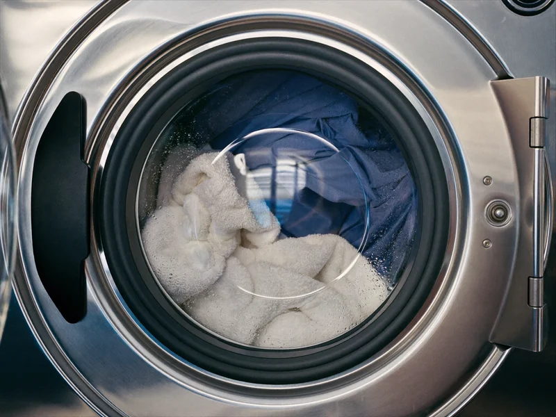 Illustration einer Industriewaschmaschine mit Wäsche in der Trommel hinter beschlagenem Glas